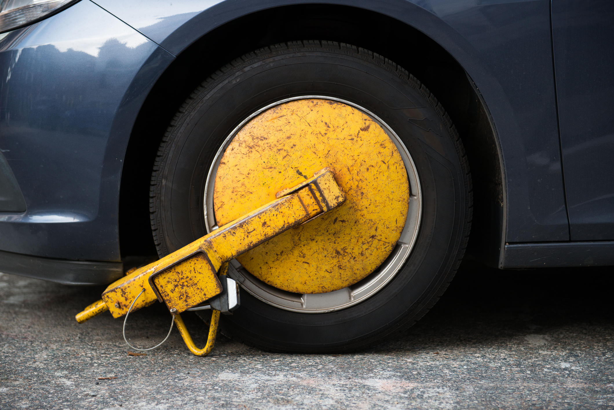 A yellow metal boot on the wheel of a car