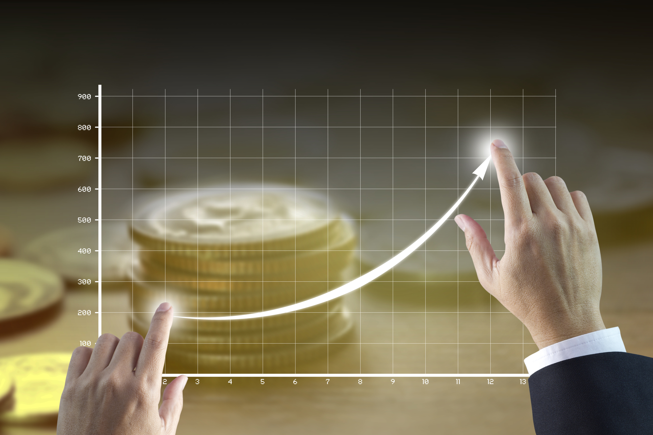 Businessman's hands touching two points on a chart that is rising quickly with coins in the background.