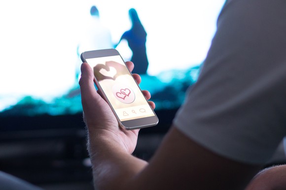Man holding a cell phone with hearts on the screen.