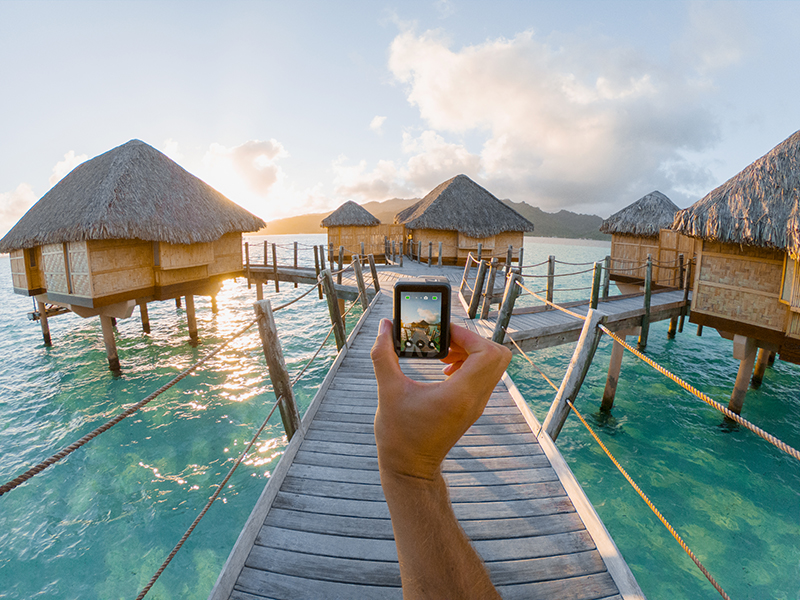 A GoPro Hero7 Black camera being held by hand walking through a Tahitian beach resort.