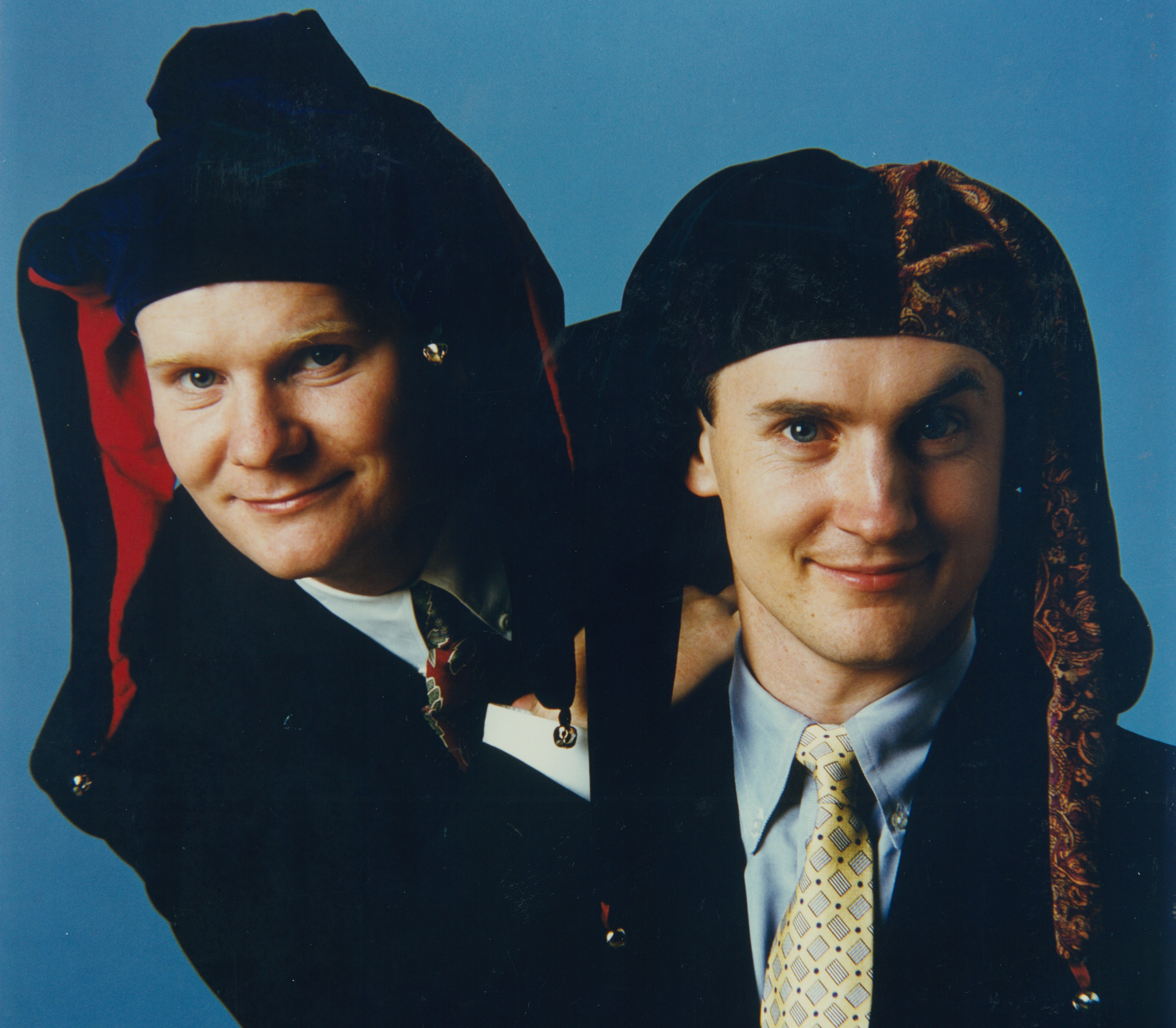 Tom and David Gardner wearing suits and jester caps