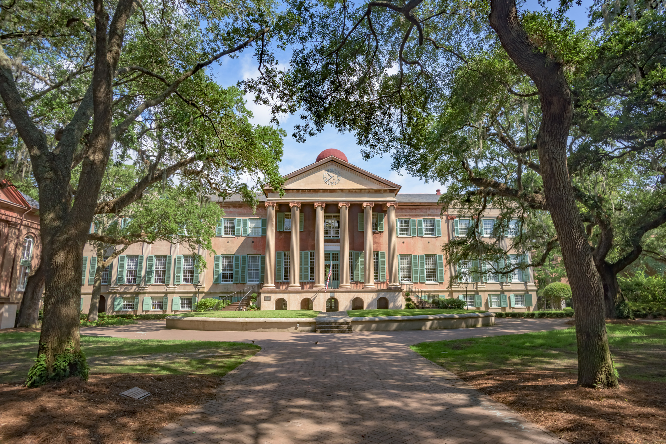 Building with pillars in front surrounded by trees.