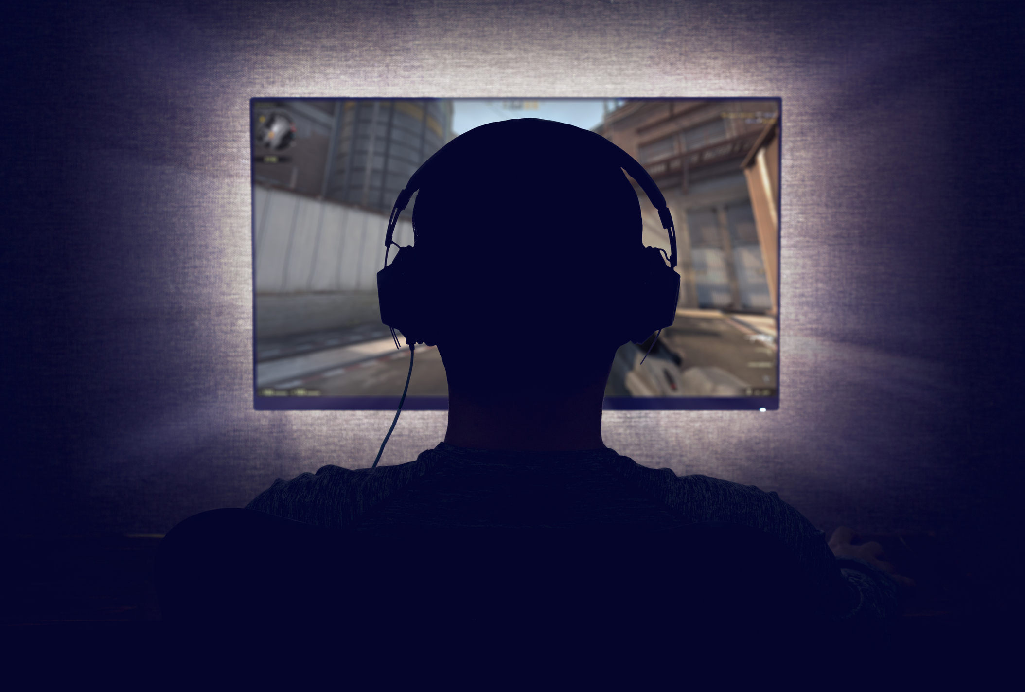 Person playing video game in a darkened room.