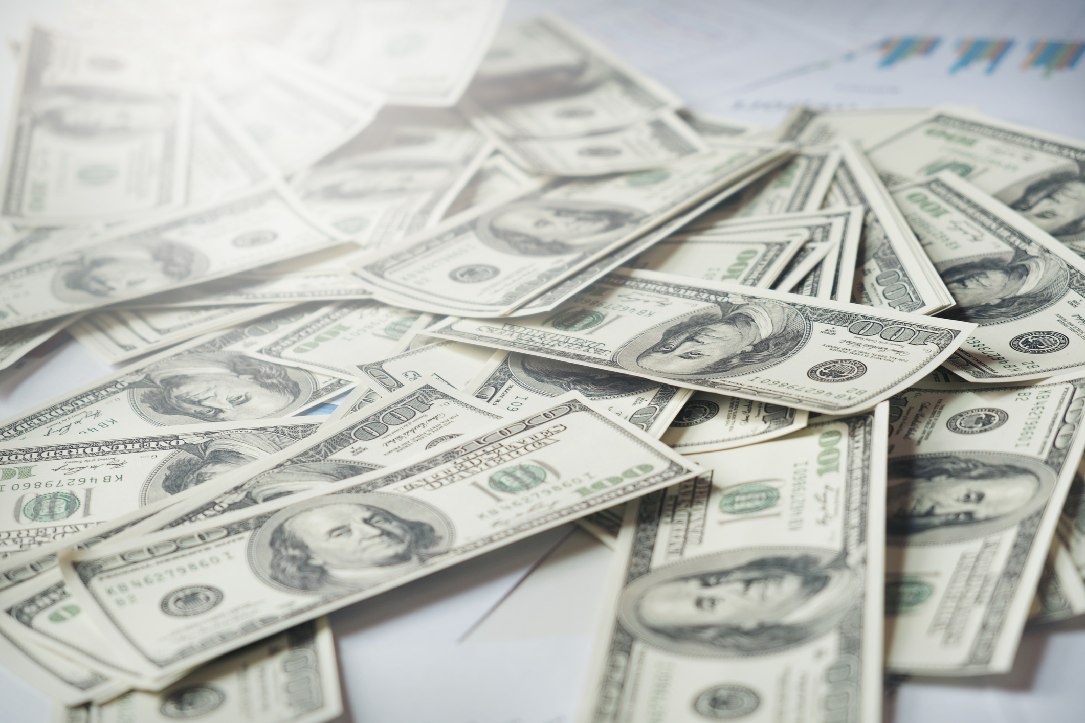 $100 bills lying loosely on a flat surface.