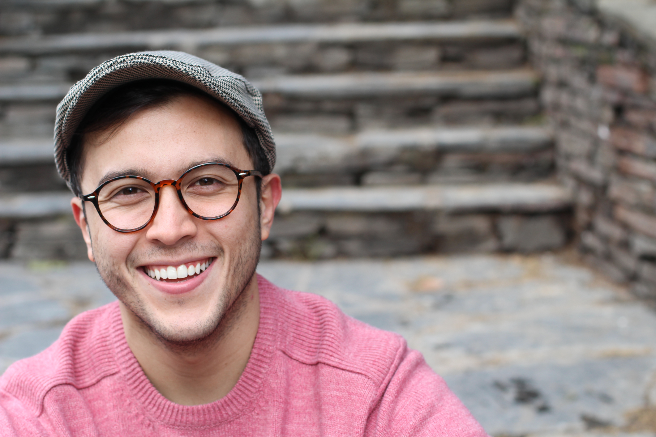 Smiling man in glasses and hat.