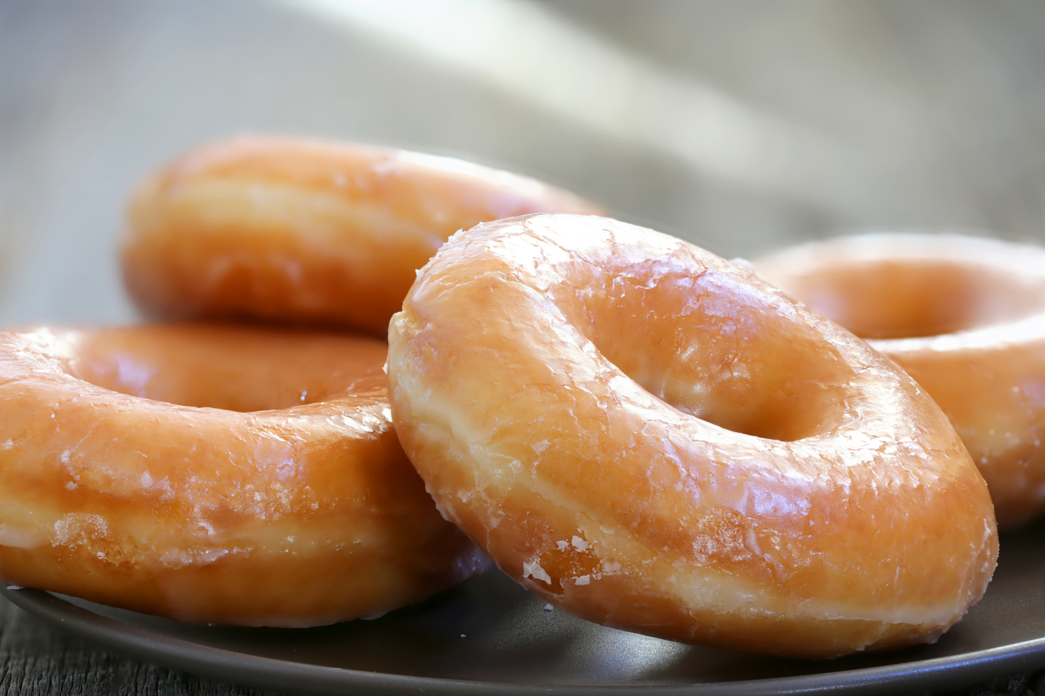 Glazed donuts piled on a plate.