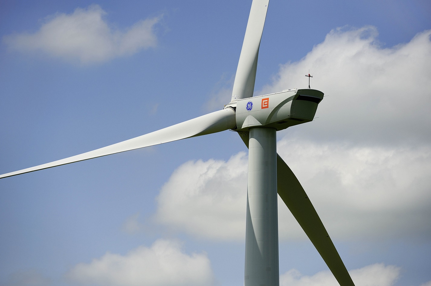 Wind turbine in front of a partly cloudy sky.