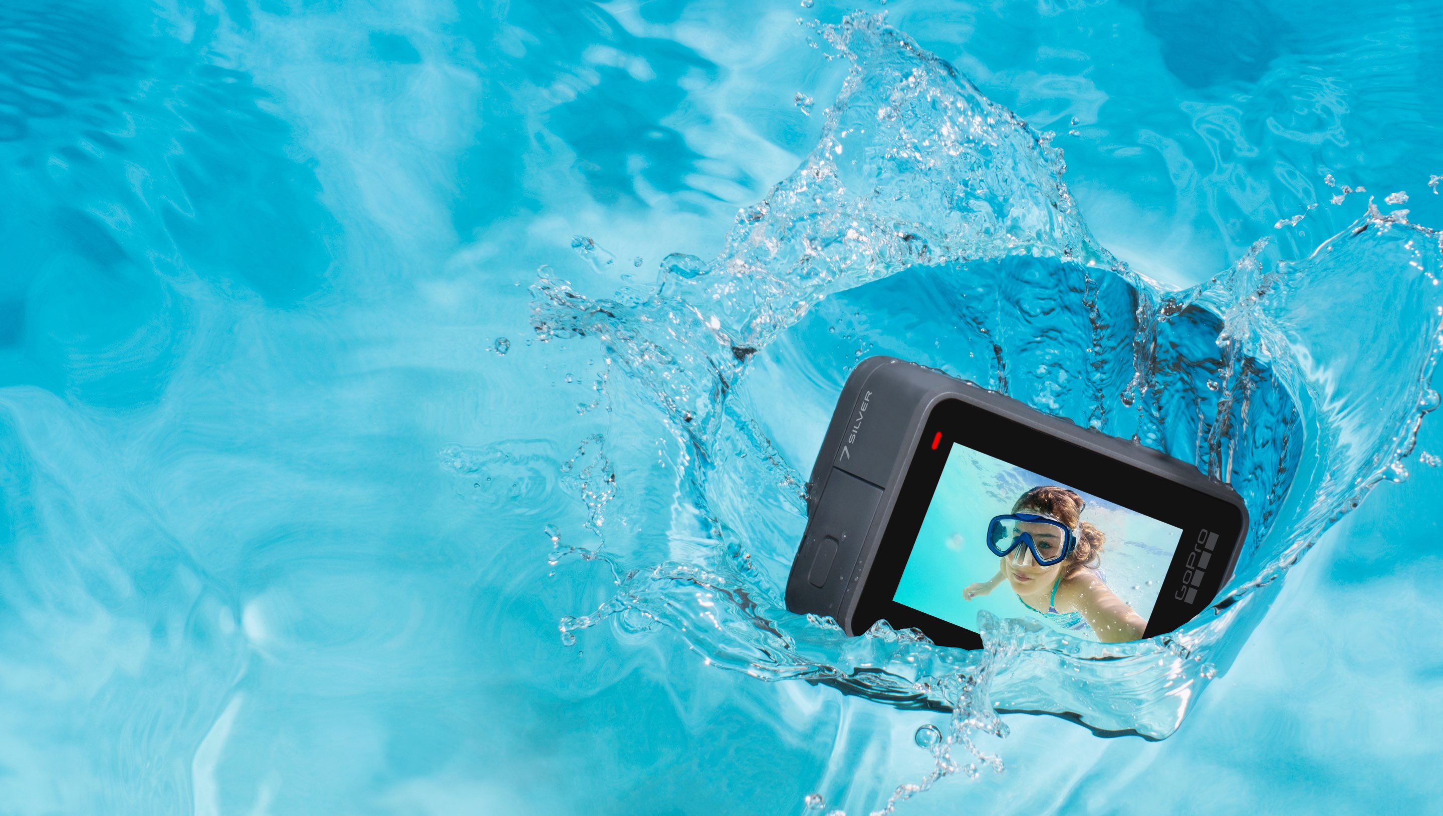 GoPro's HERO7 Silver camera falling into blue water with an image of a scuba diver on its display