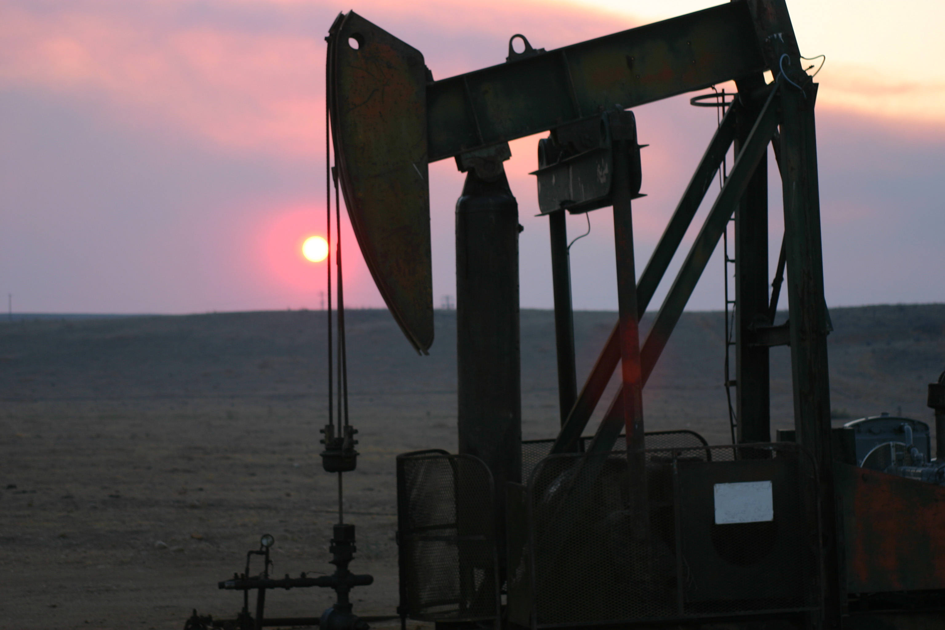 An oil pump with the sun setting in the background.