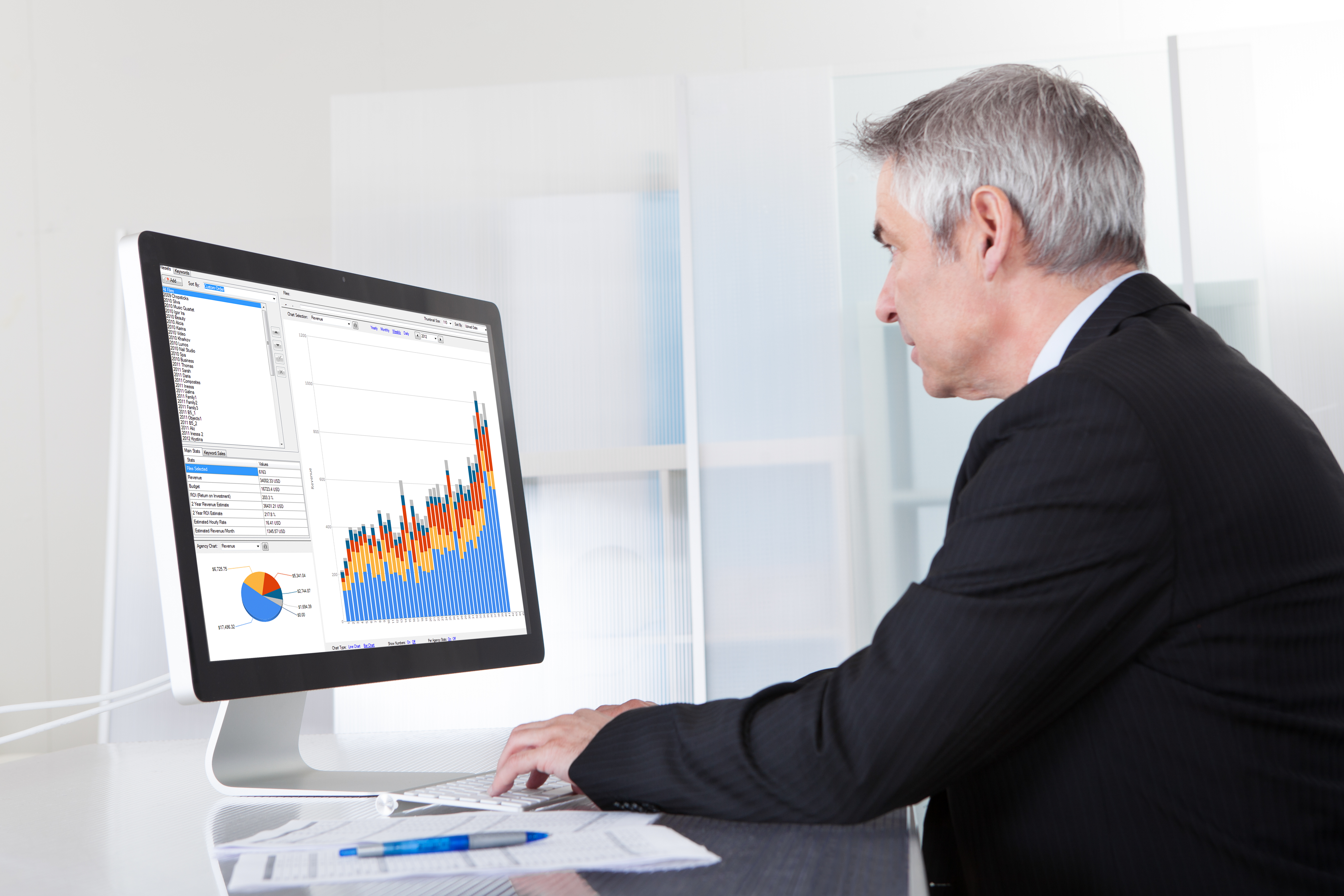 Senior man looking at computer screen with graphs and charts.