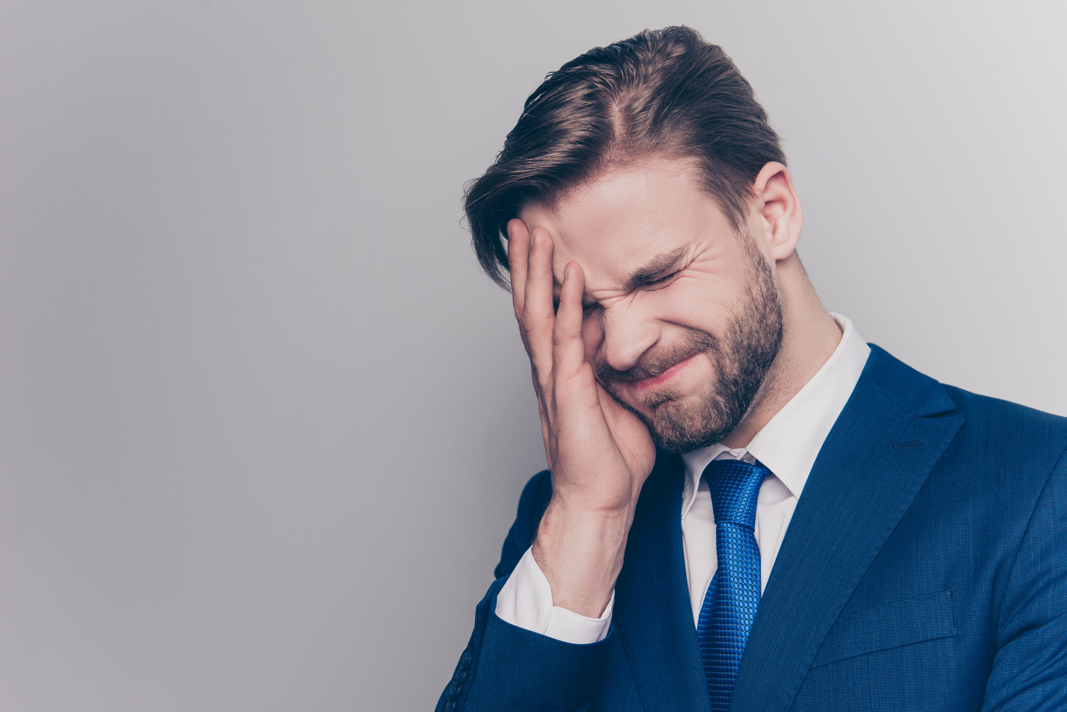 Business man looking stressed and holding his face.