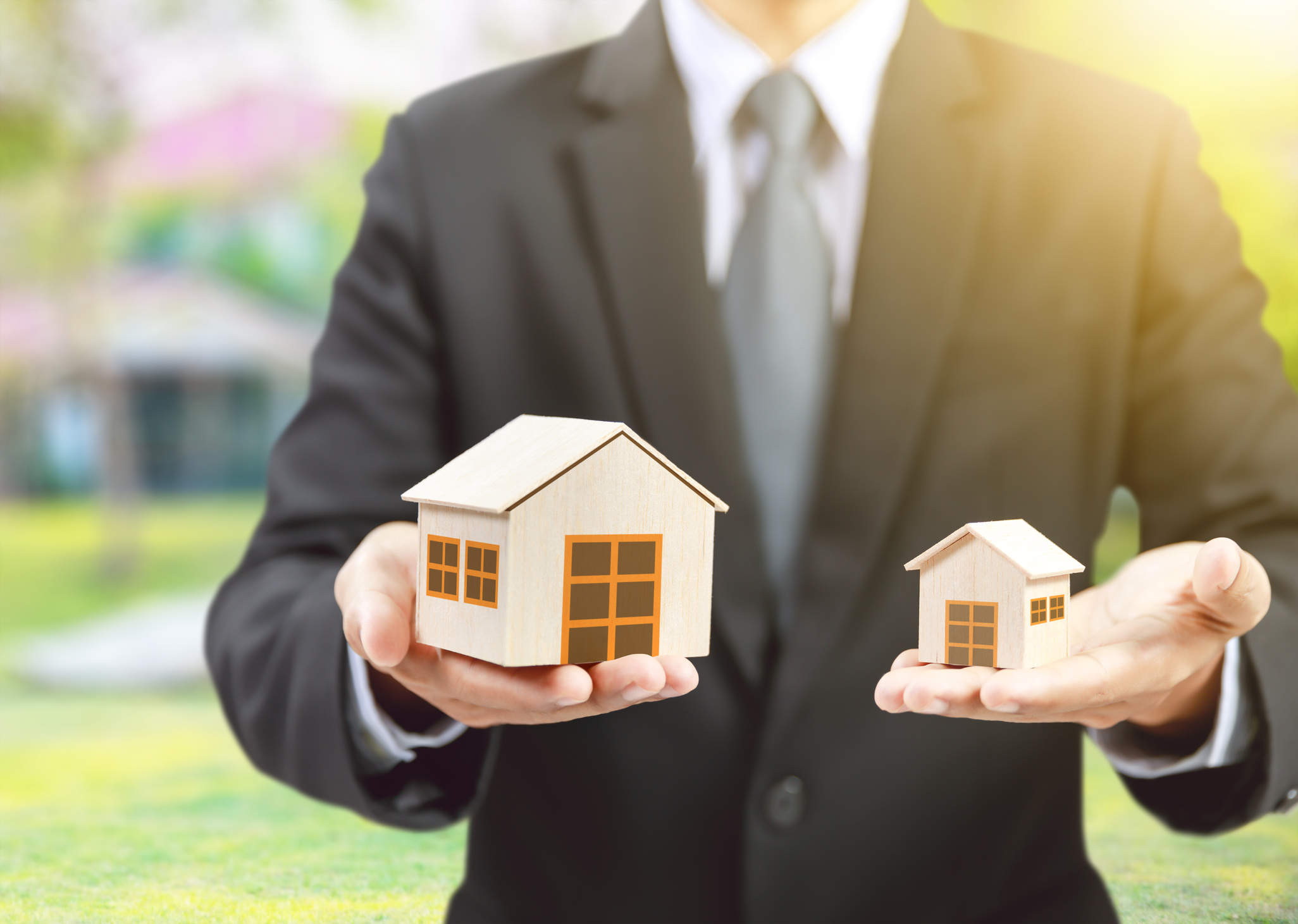 A person holding two different sized miniature houses.