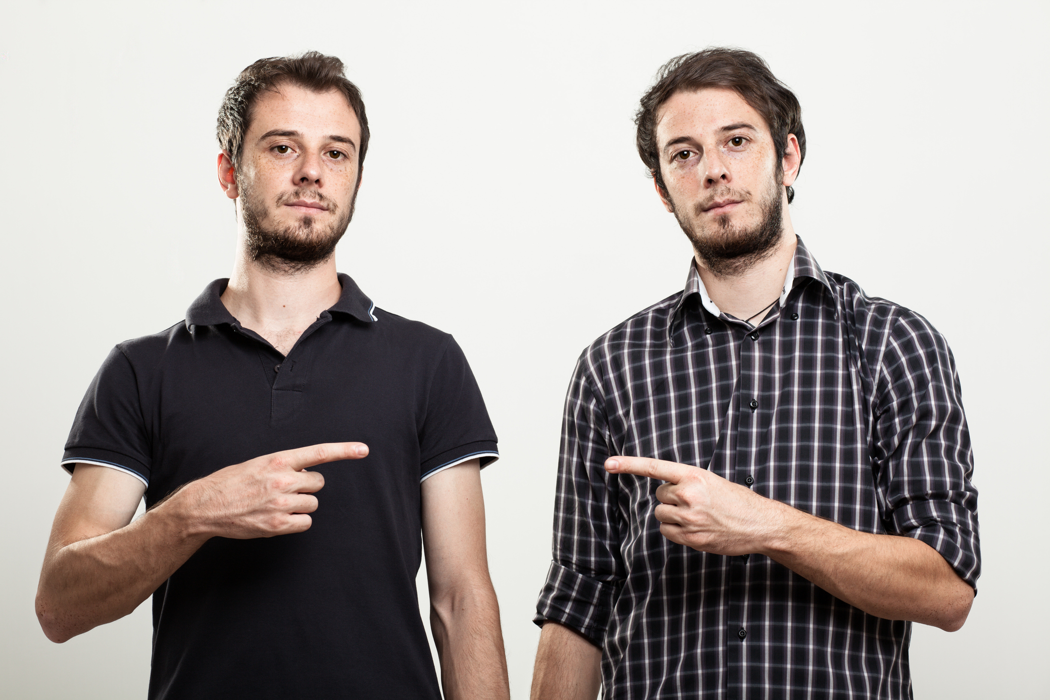 Two twins pointing at each other