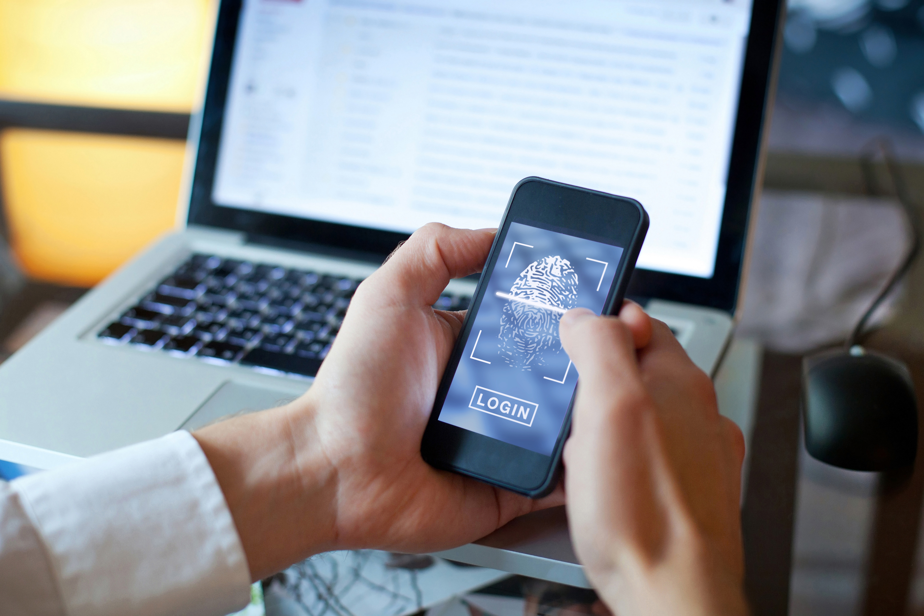 A person holds a smartphone that contains a login screen.