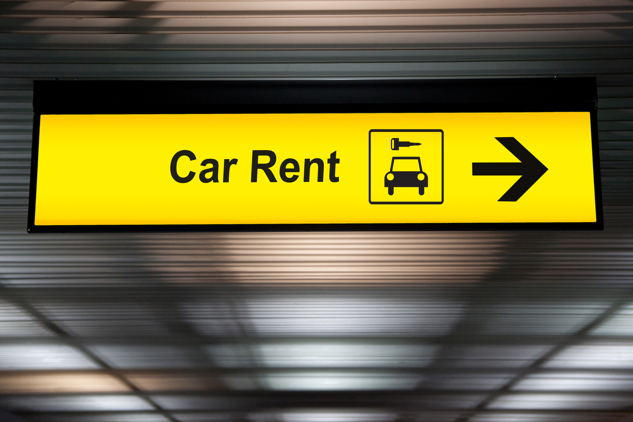 Yellow "car rent" sign at an airport.