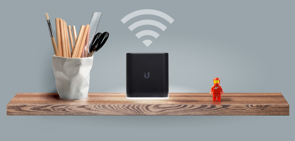 Black Ubiquiti Networks router on a wooden shelf.