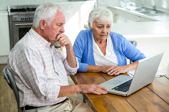 Senior couple looking at laptop with concerned expressions.