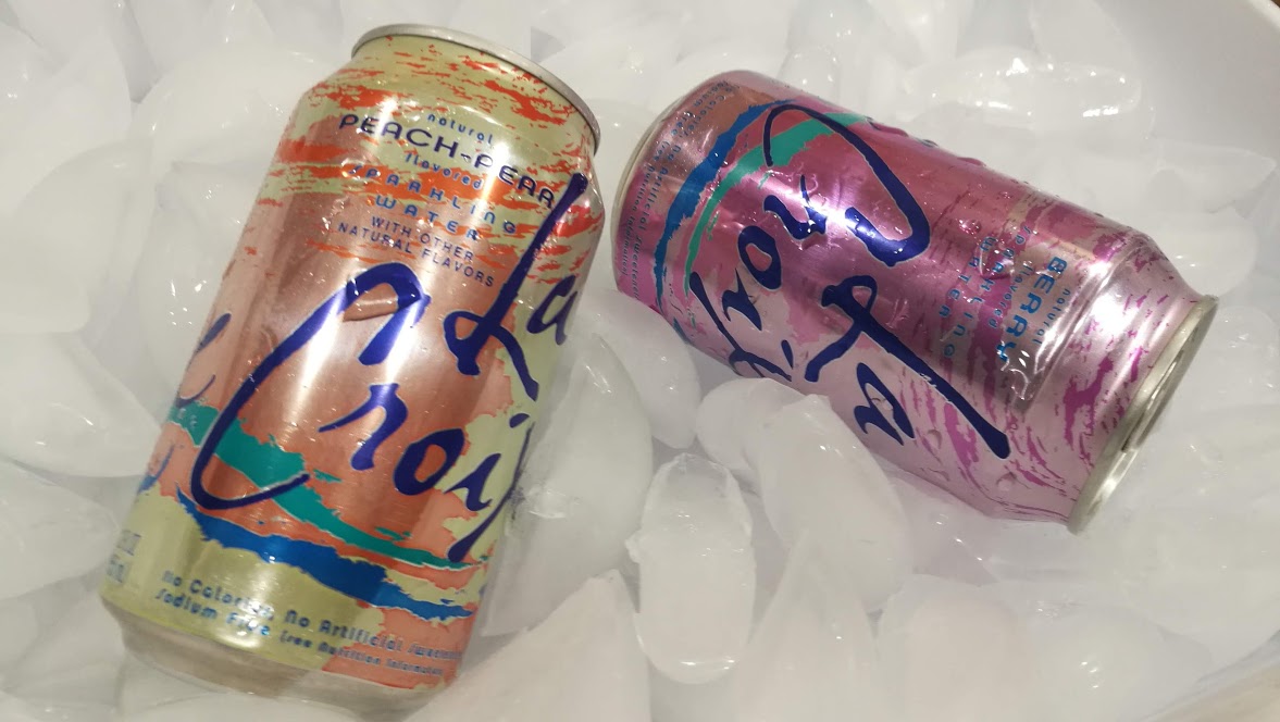 Two cans of LaCroix resting on a bed of ice cubes.