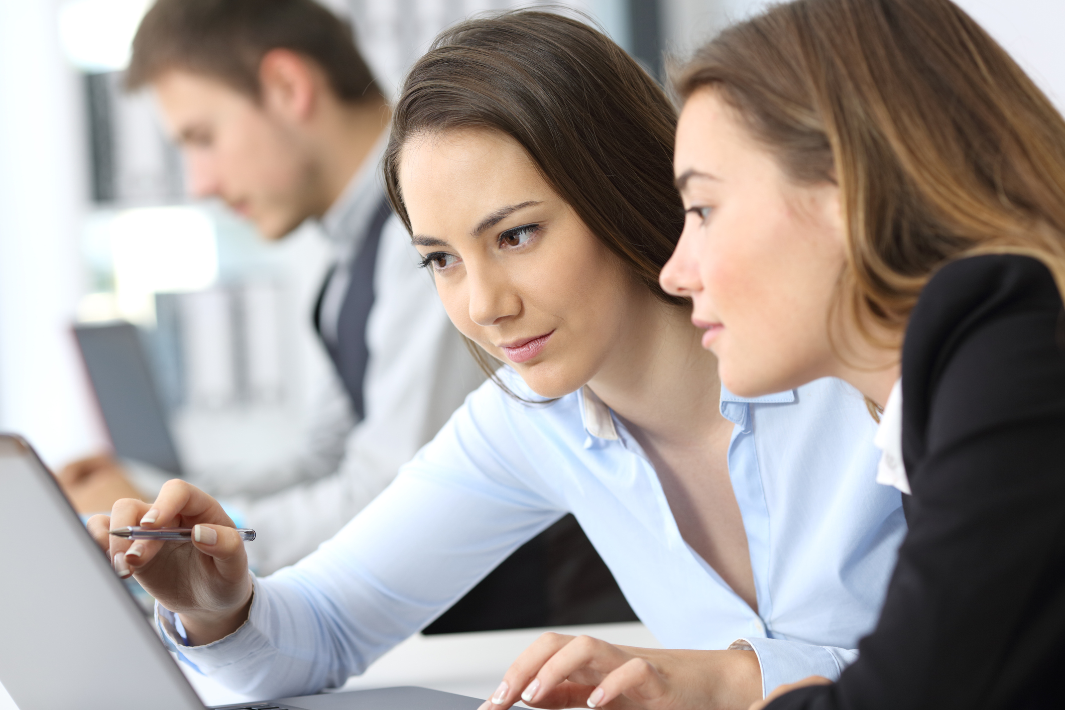 One woman shows another something on a computer.