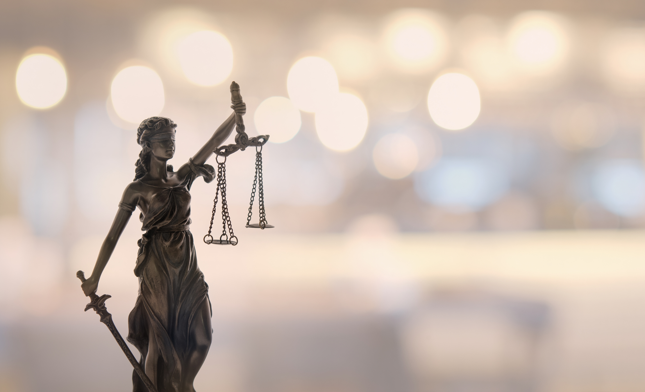 Statue of Lady Justice with blurred lights in the background