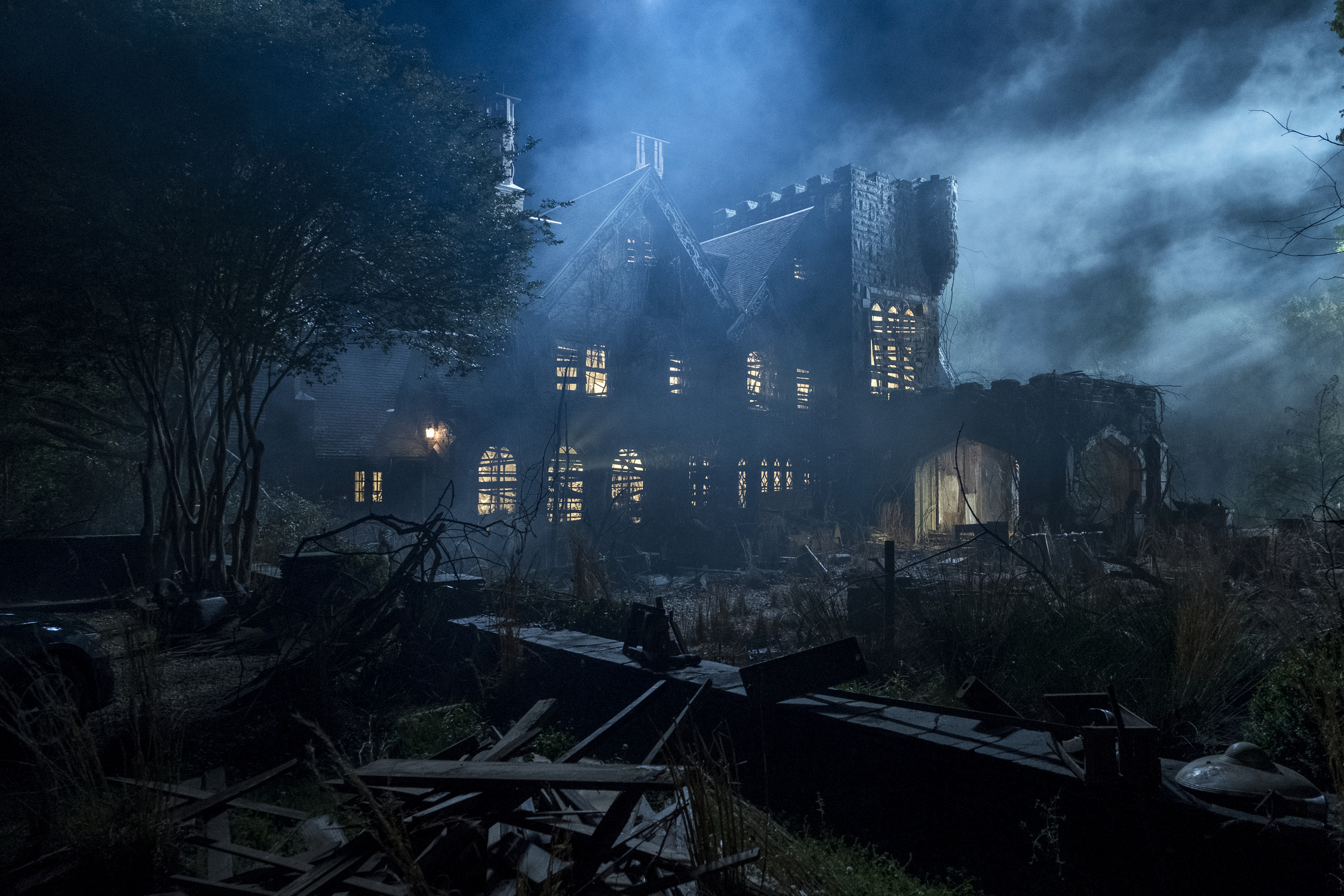A Gothic house on a dark, cloudy night, lit by moonlight.