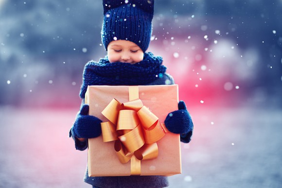 A boy holding a gift with a bow on it.