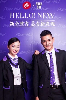 Two Pizza Hut employees wearing the new formal wear by Anna Sui. Both are wearing dark black suits with purple accents.