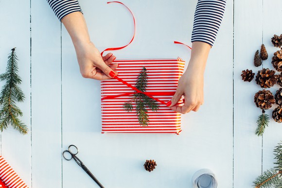Woman tying bow on wrapped gift