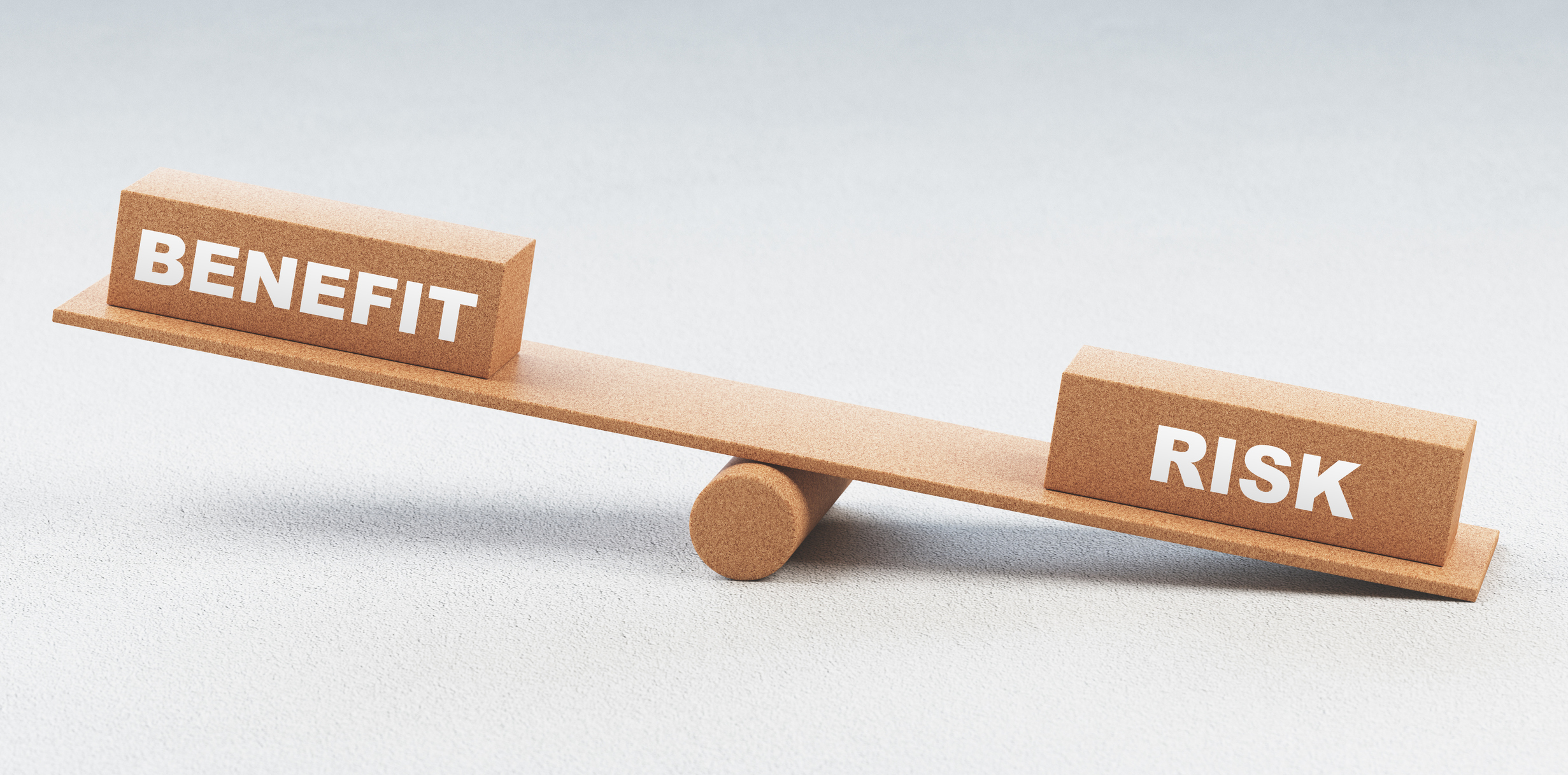 A wooden balance holding blocks labeled Benefit and Risk
