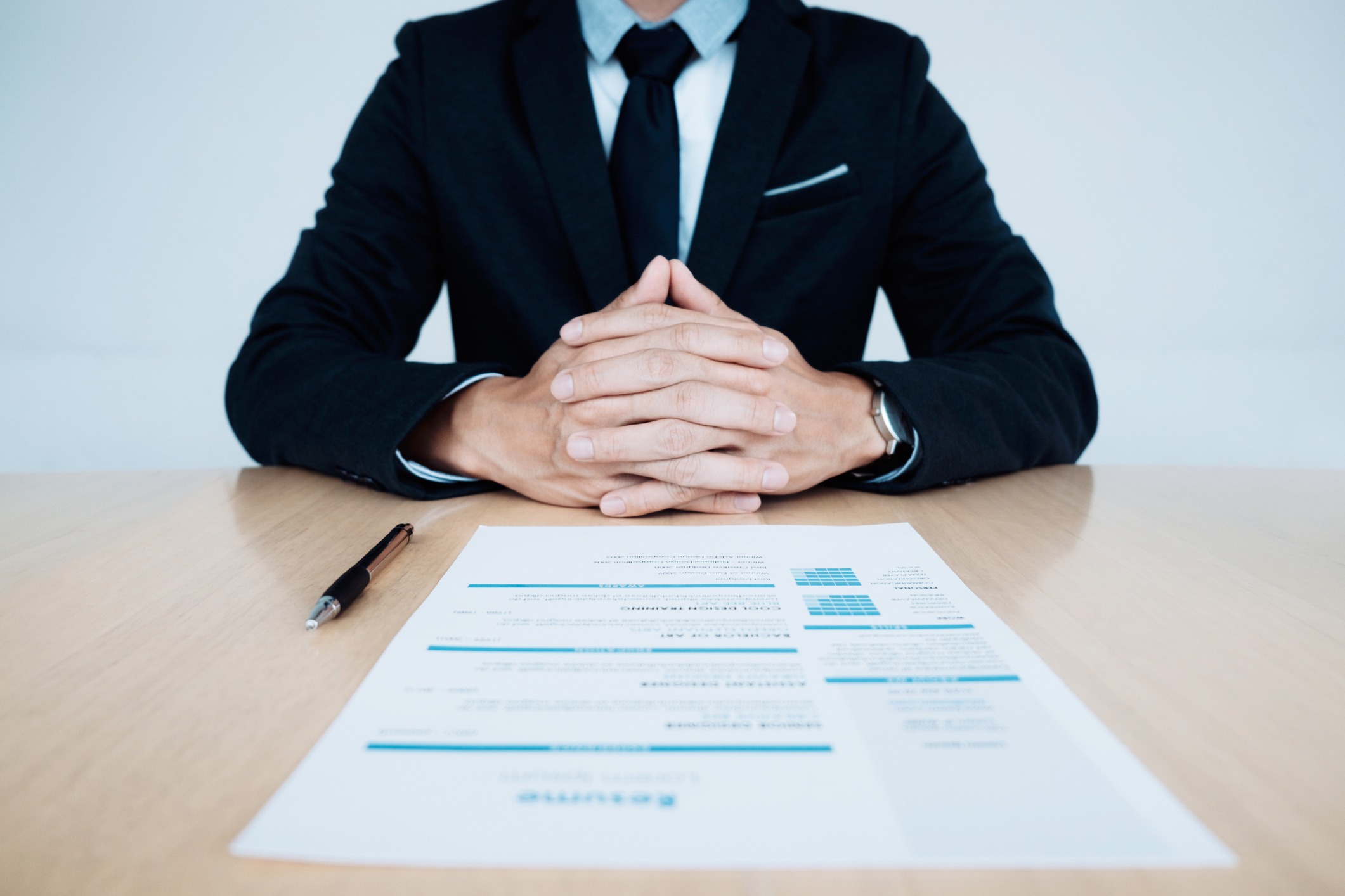 Man in suit sitting at table with document in front of him.