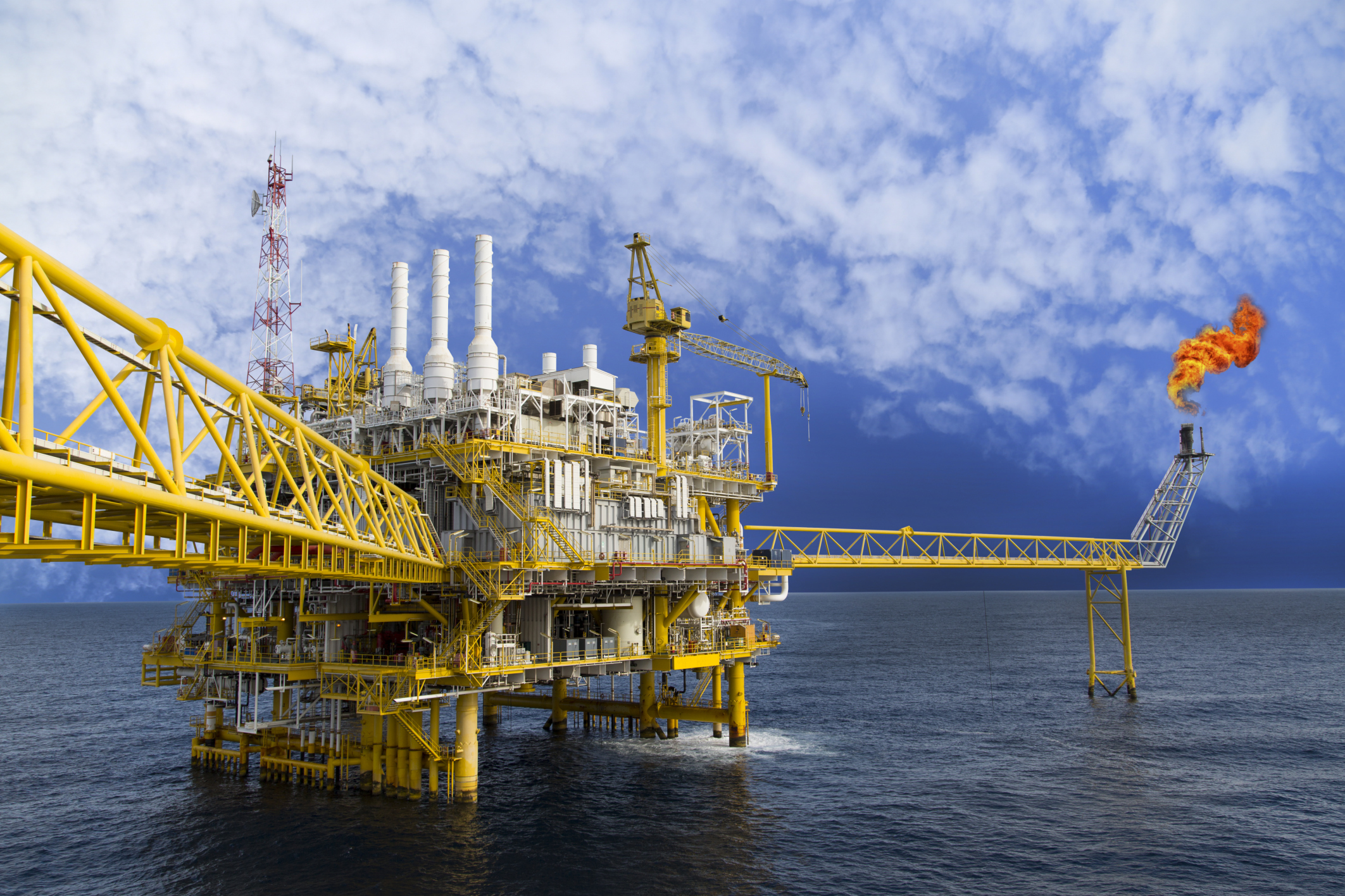 A yellow oil rig in the middle of the ocean.