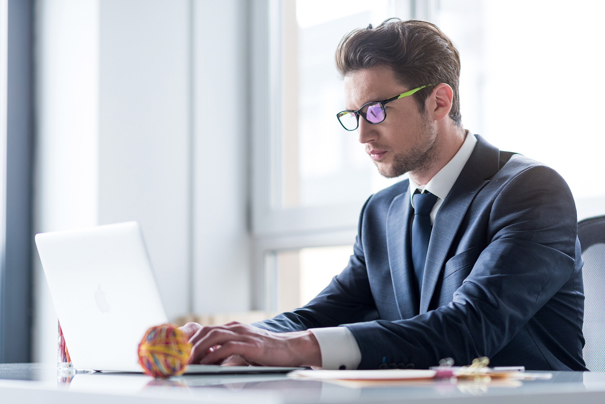 Man in suit typing on laptop.