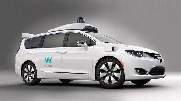 White minivan with self-driving technology on it and Waymo logo on the sliding door.