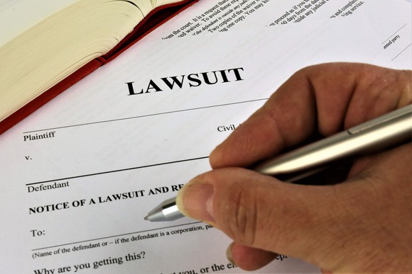 A person filling out lawsuit paperwork.