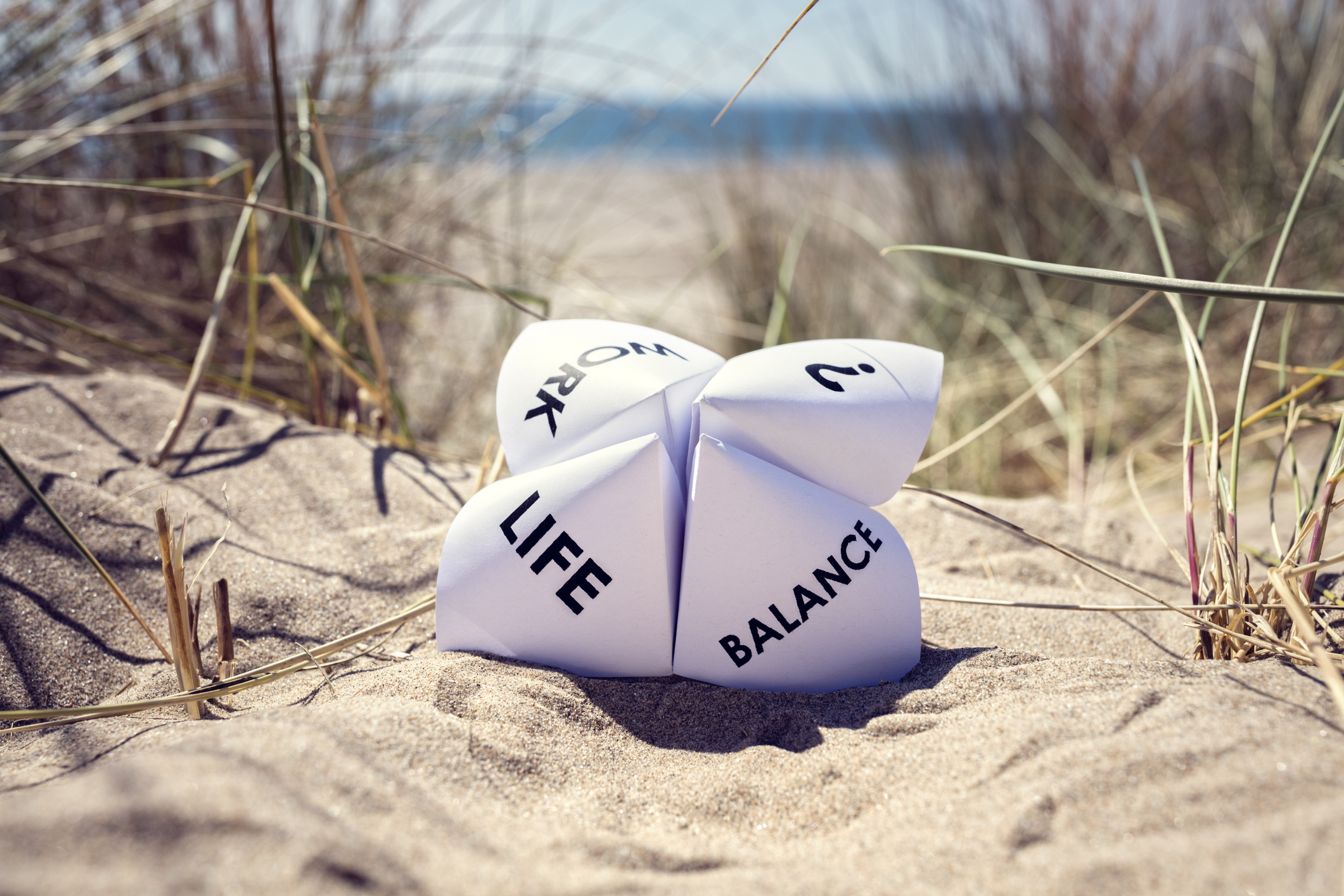A piece of paper in beach sand with the words life and balance written on it.