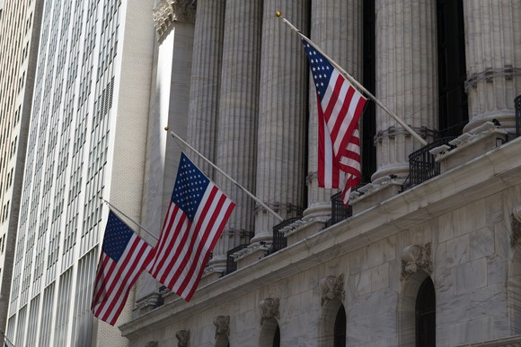 Front of New York Stock Exchange, with three U.S. flags hanging.