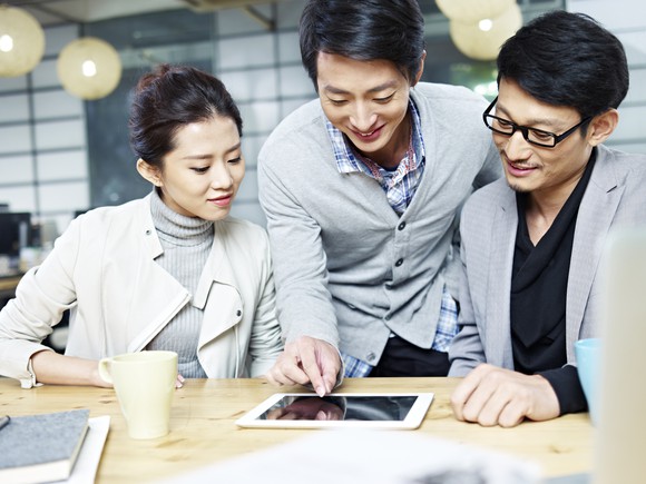 A group of professionals search for information a tablet.