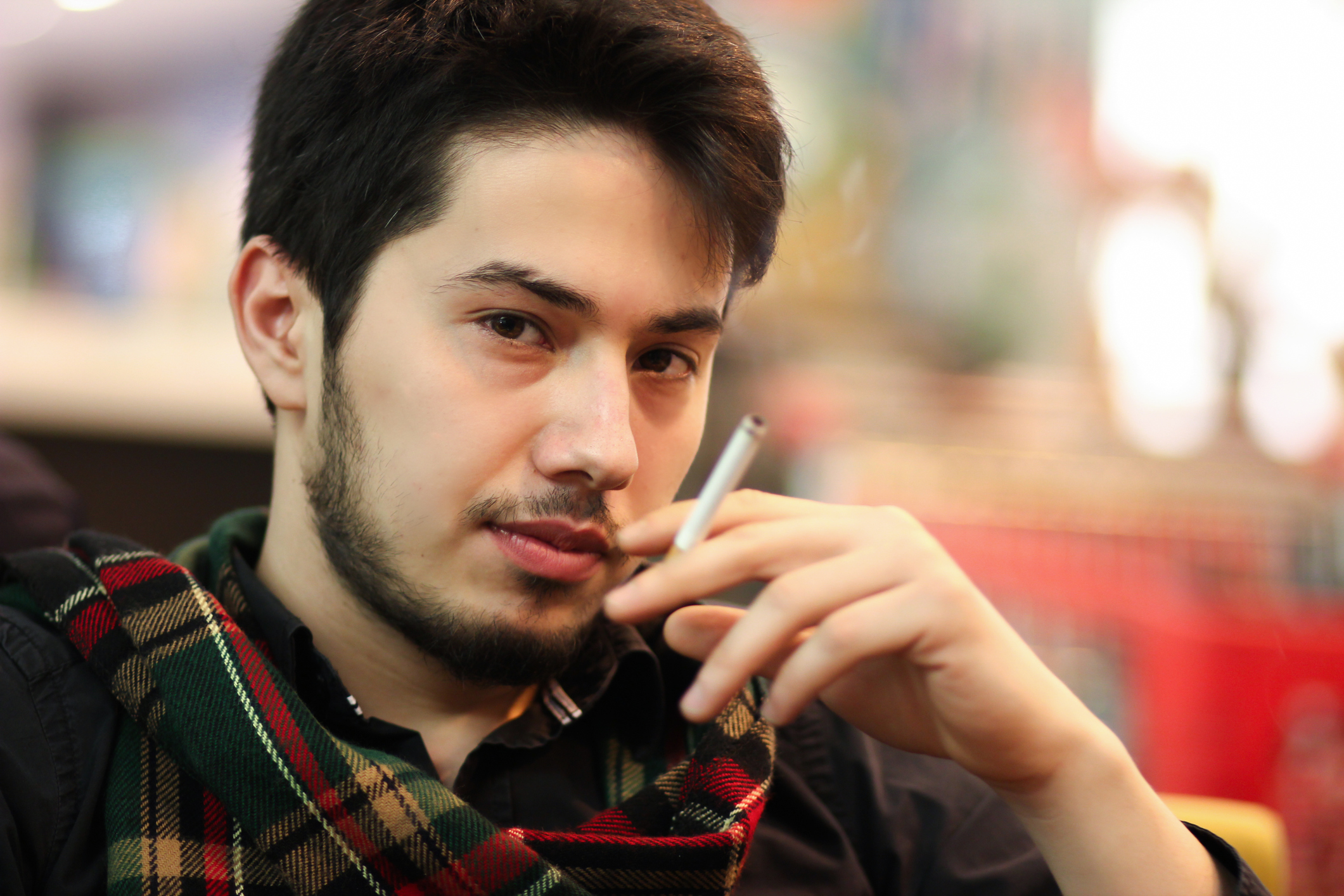 A young man smoking a tobacco cigarette.