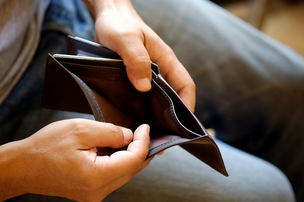 A pair of hands holding out an empty wallet.