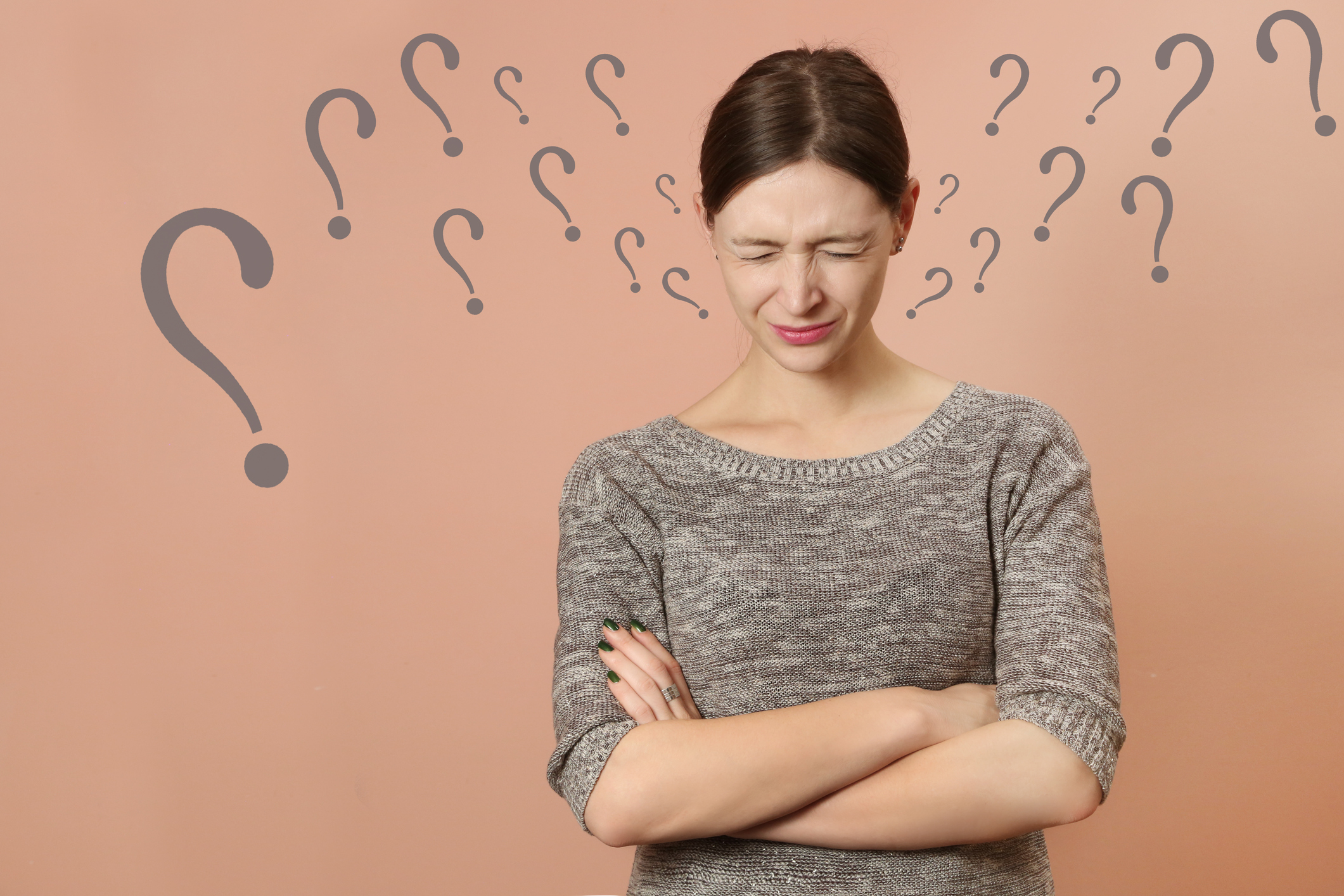 A woman with her eyes closed in deep thought with question marks surrounding her head.