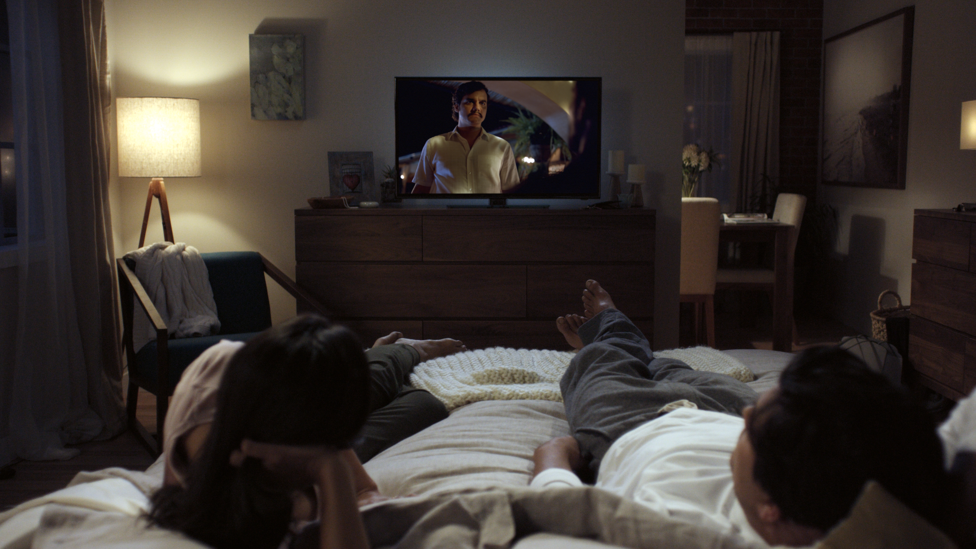 A couple watching Netflix in their bedroom.