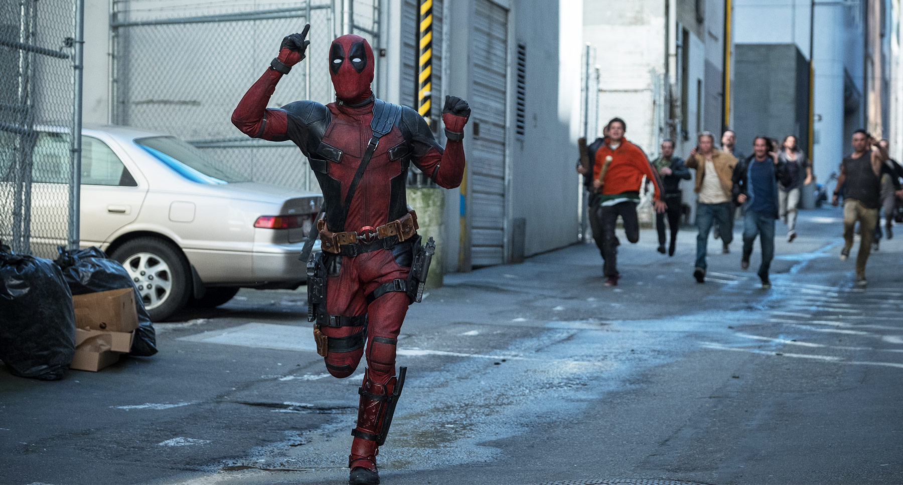 Deadpool runs down an alley.