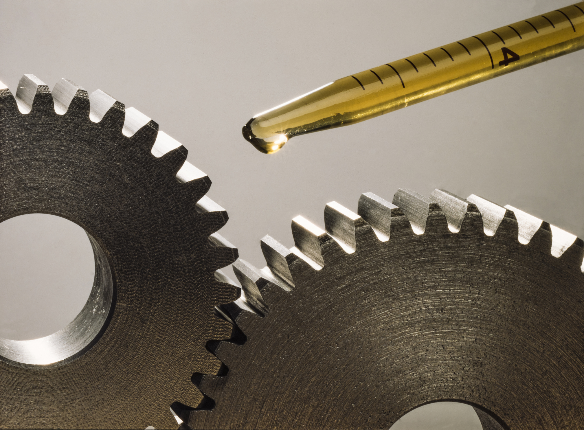 Two pinions are lubricated with a drop of oil from a test tube.
