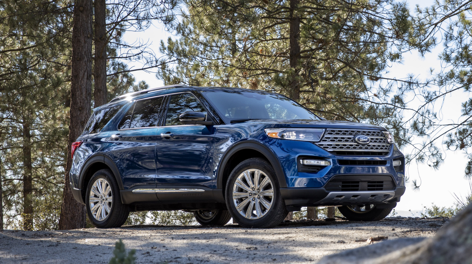 A blue 2020 Ford Explorer, a midsize crossover SUV, parked in a wooded setting.