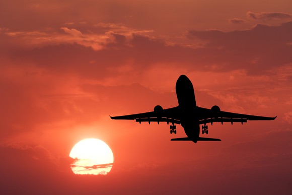 A plane flying in a sky at sunset.