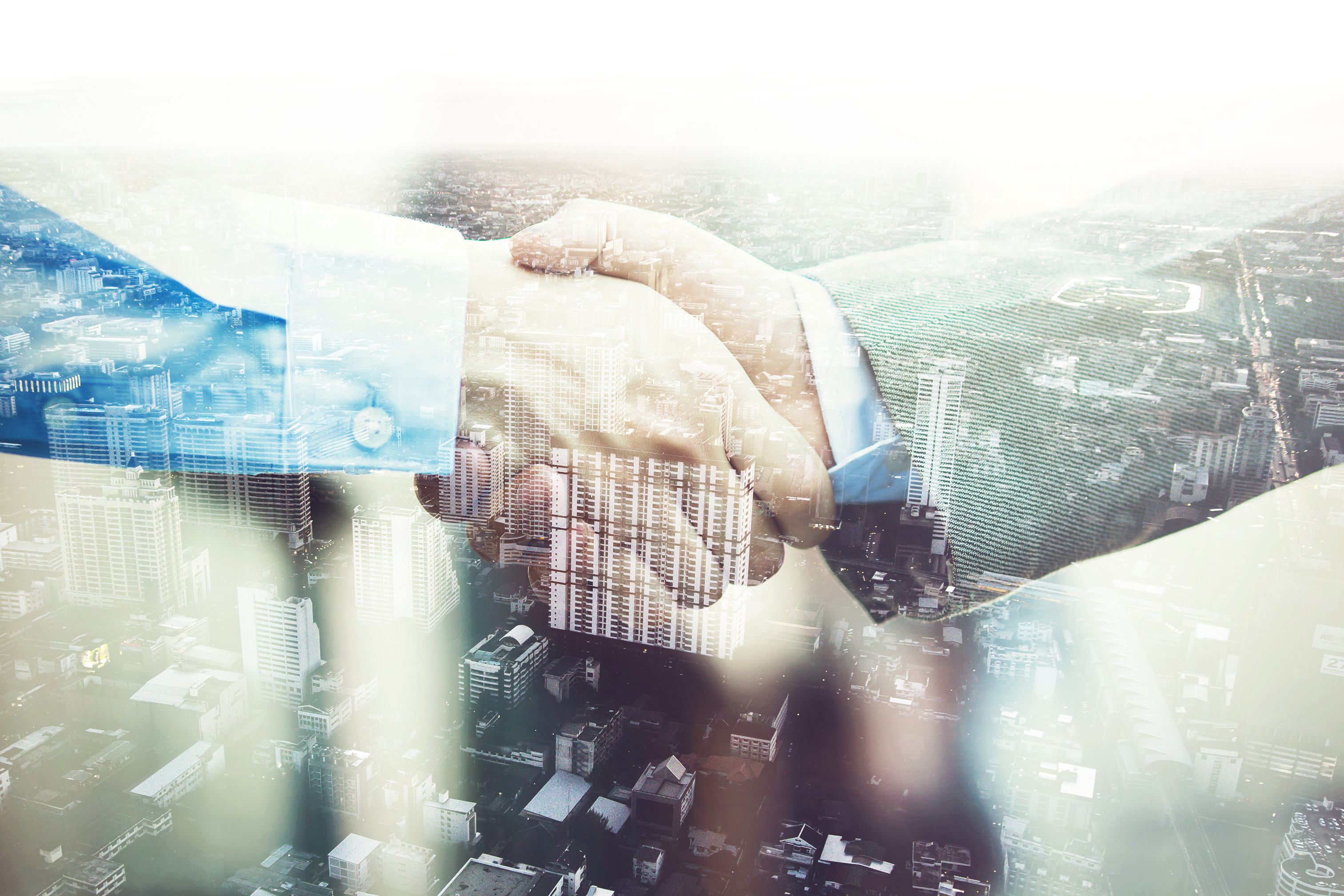 Two businessmen shaking hands over a city background.