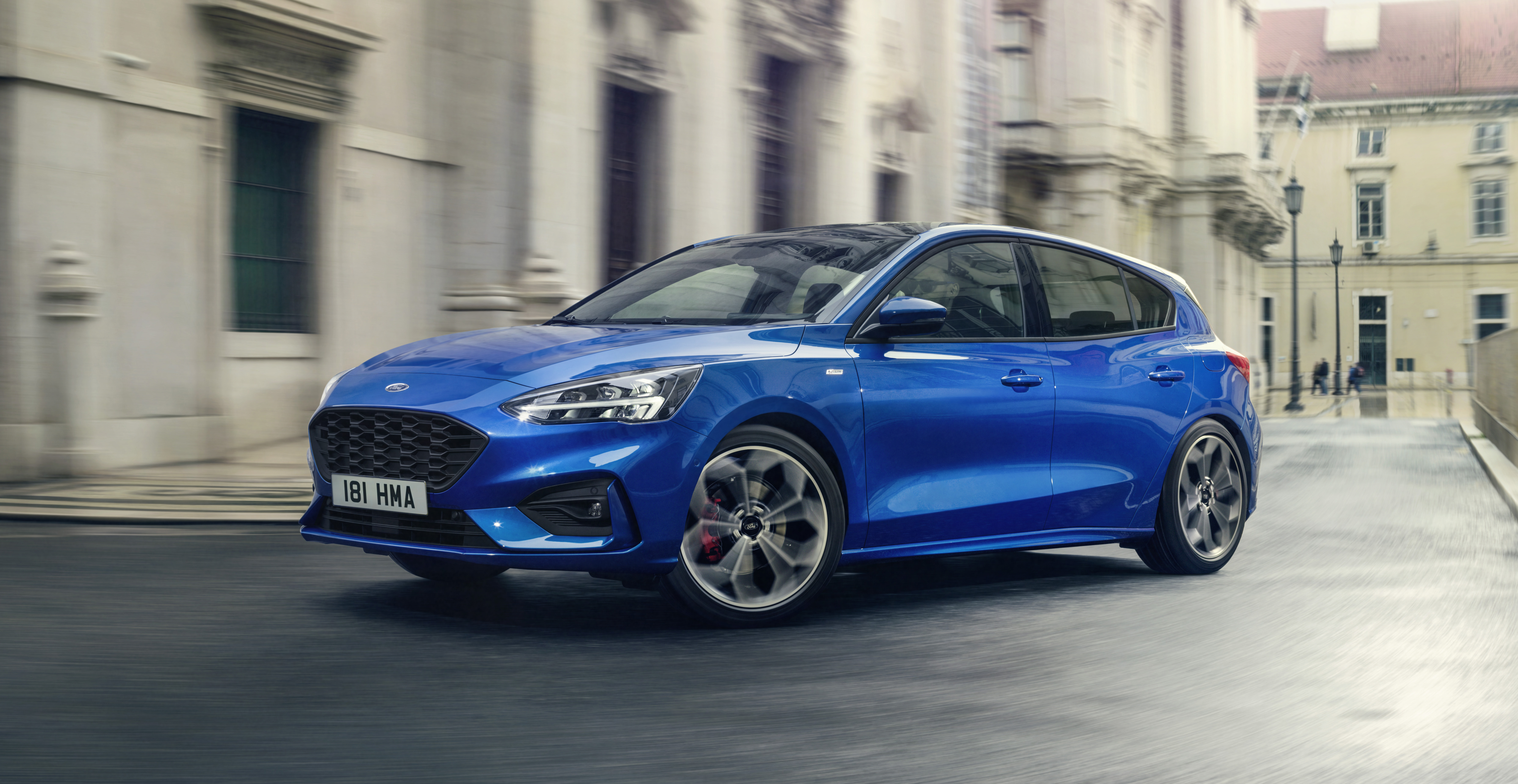 A blue 2019 Ford Focus ST, a sporty hatchback, on a European street.