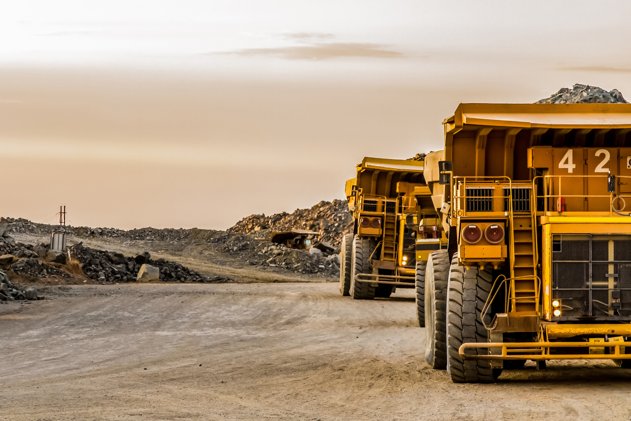 Mining trucks standing next to a mine.