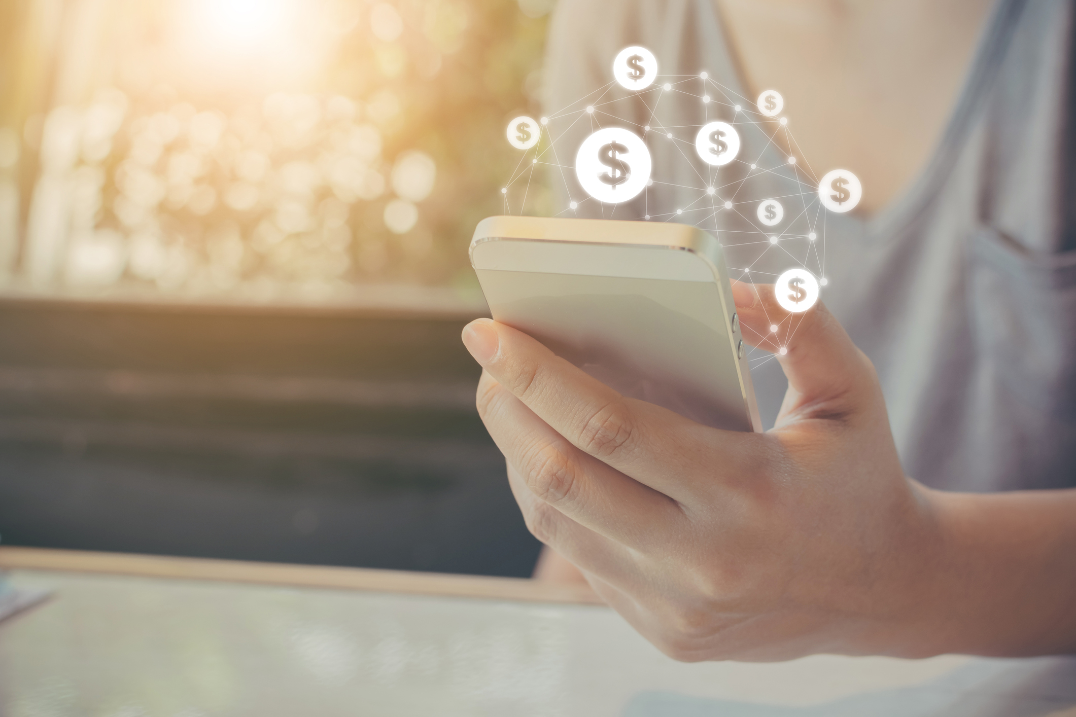 Dollar signs floating out of a smartphone.