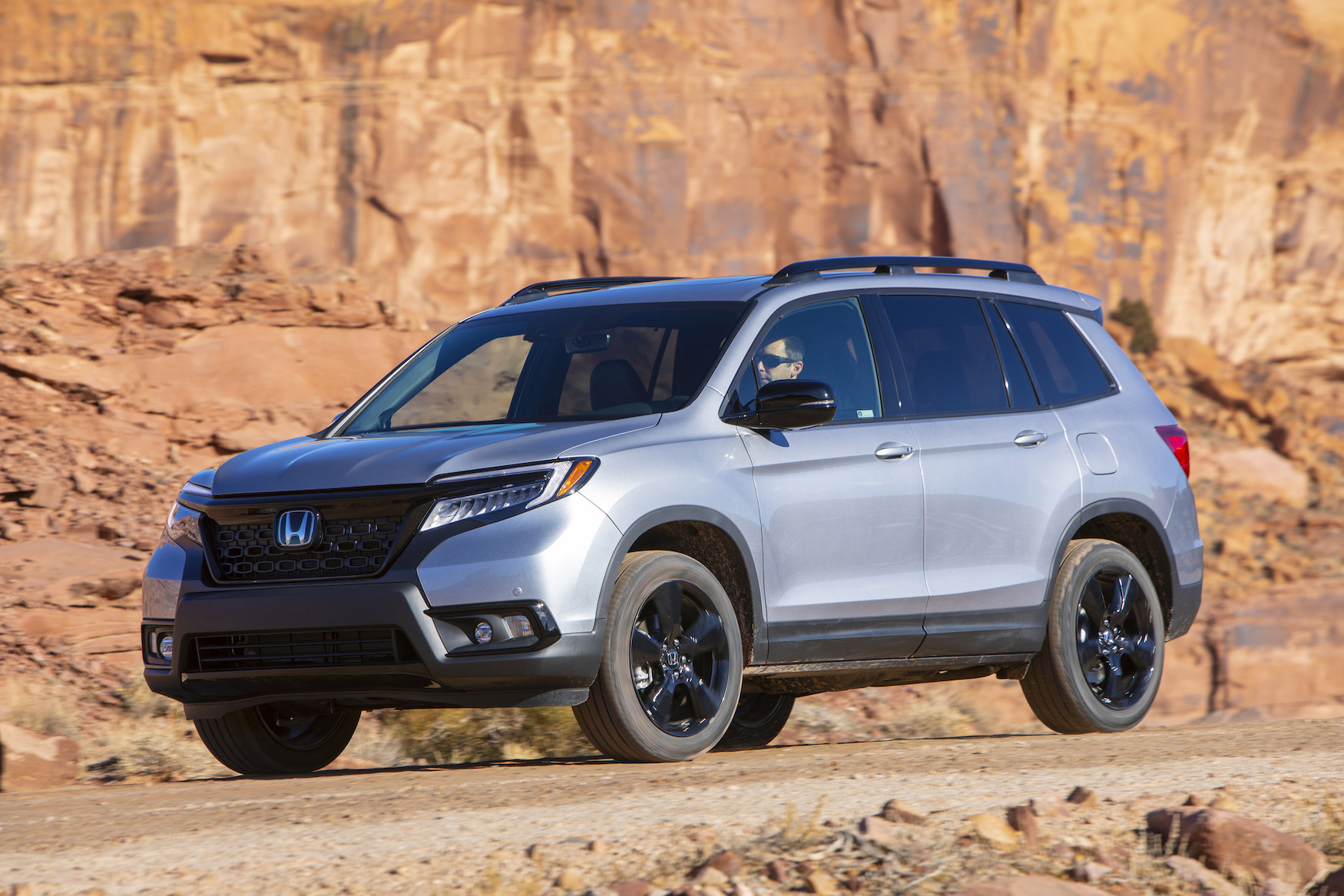 A silver 2019 Honda Passport, a five-passenger midsize crossover SUV, in a desert setting.